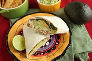 A chicken and avocado wrap with beans, cheese, and cilantro inside.