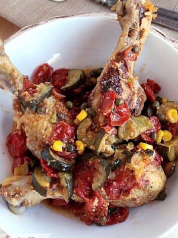 An overhead photo of a bowl of Italian Chicken Legs with tomatoes and zucchini.