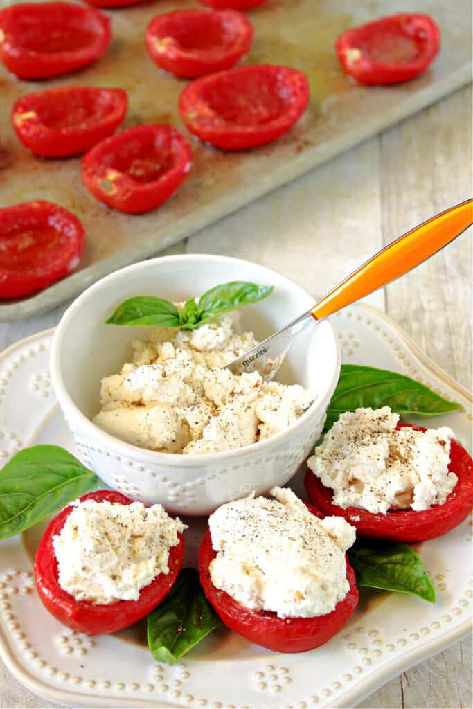 A vertical closeup of Roasted Roma Tomatoes with Homemade Red Pepper Ricotta in a bowl and stuffed into the tomatoes themselves.