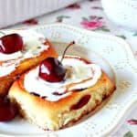 Two Cherry Sweet Rolls on a white plate with fresh cherries on top as garnish.