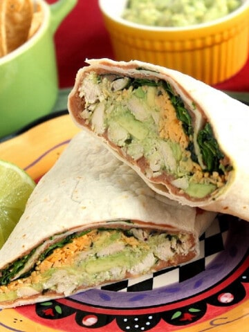 A Chicken Avocado Wrap cut in half on a colorful plate.