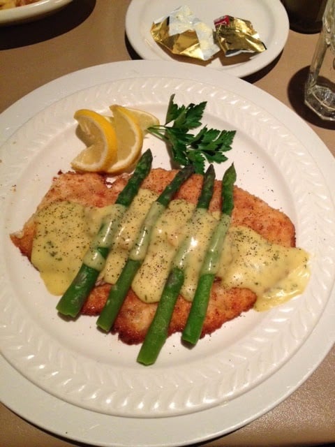 A white dinner plate with chicken oscar.