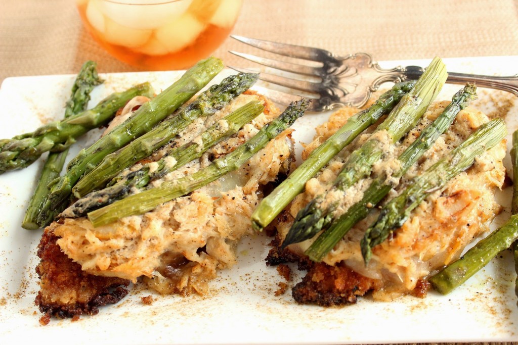 Two chicken Oscar on a plate with crab meat and asparagus topping