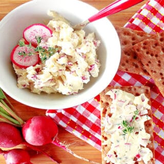 A horizontal photo of a small bowl of Compound Radish Butter with Thyme along with fresh radishes and a red and white checked napkin.