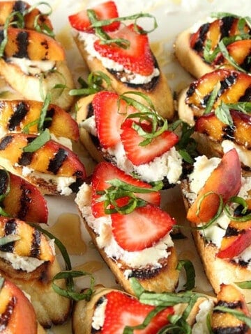A pretty plate filled with Goat Cheese Crostini with grilled nectarines and strawberries.