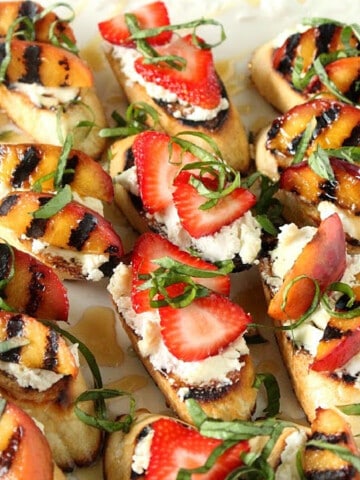 A pretty plate filled with Goat Cheese Crostini with grilled nectarines and strawberries.