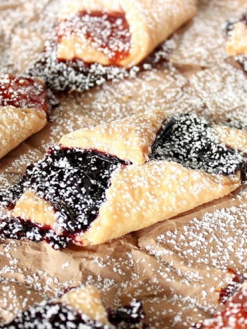 A closeup of Cream Cheese Kolaches on a brown bag dusted with powdered sugar.