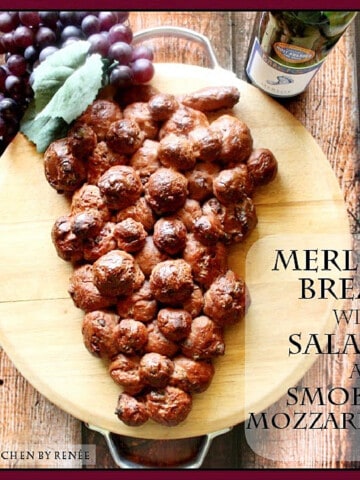 A loaf of Merlot Bread shaped like a bunch of grapes on a round cutting board.