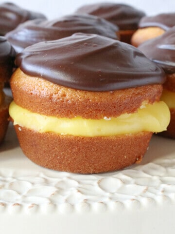 A closeup of a Boston Cream Cupcake topped with chocolate ganache.