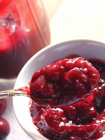 A white bowl and spoon filled with Homemade Cherry BBQ Sauce