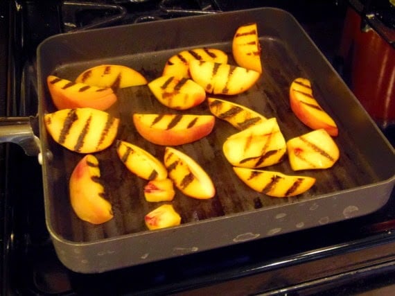 Peach slices with grill marks in a grill pan.