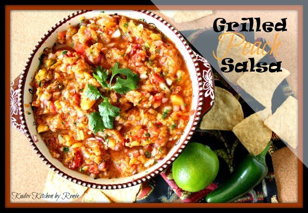 An overhead photo of a bowl full of grilled peach salsa with chips, a lime, and a jalapeno pepper on the side.