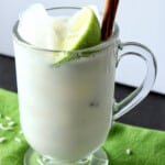 A mug of Homemade Horchata with a lime wedge and cinnamon stick.