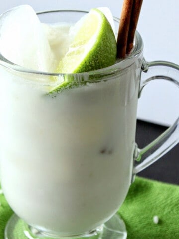 A mug of Homemade Horchata with a lime wedge and cinnamon stick.