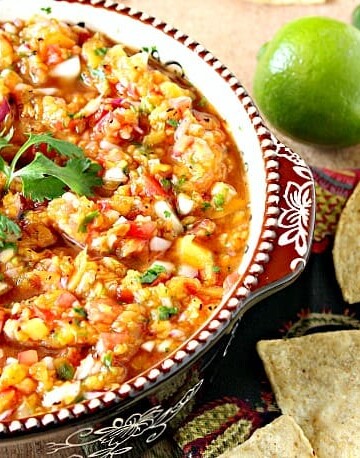 Fresh peach salsa in a bowl with cilantro, chips, lime and jalapeno