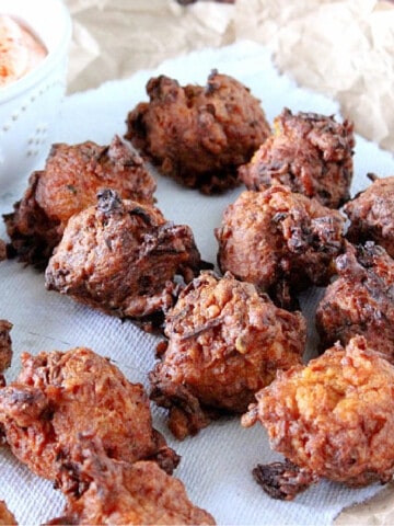 A bunch of Zucchini and Sweet Potato Fritters on a paper bag and napkin.