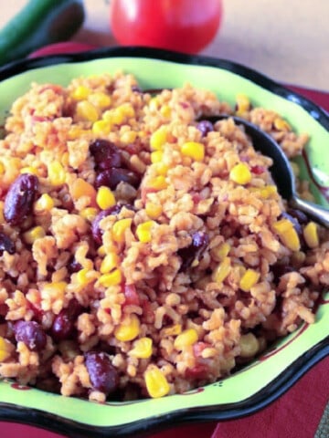 A green bowl filled with Brown Rice and Beans along with a spoon.
