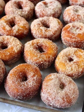 A bunch of Mashed Sweet Potato Donuts lined up on a baking sheet.