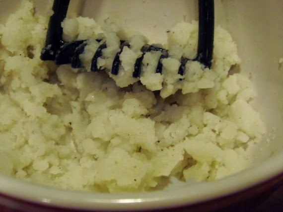 Mashed potatoes in a bowl with a masher.