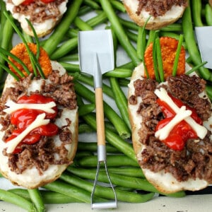 Two Twice Baked Potato Graves with a shovel fork on top of green beans.