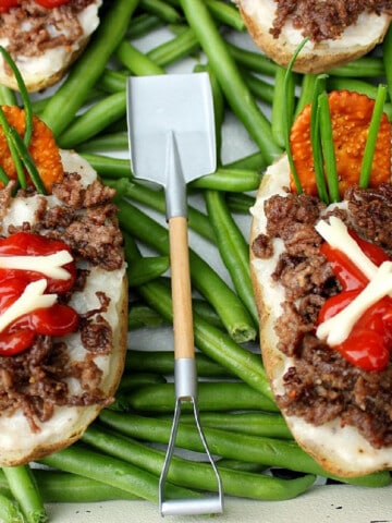 Two Twice Baked Potato Graves with a shovel fork on top of green beans.