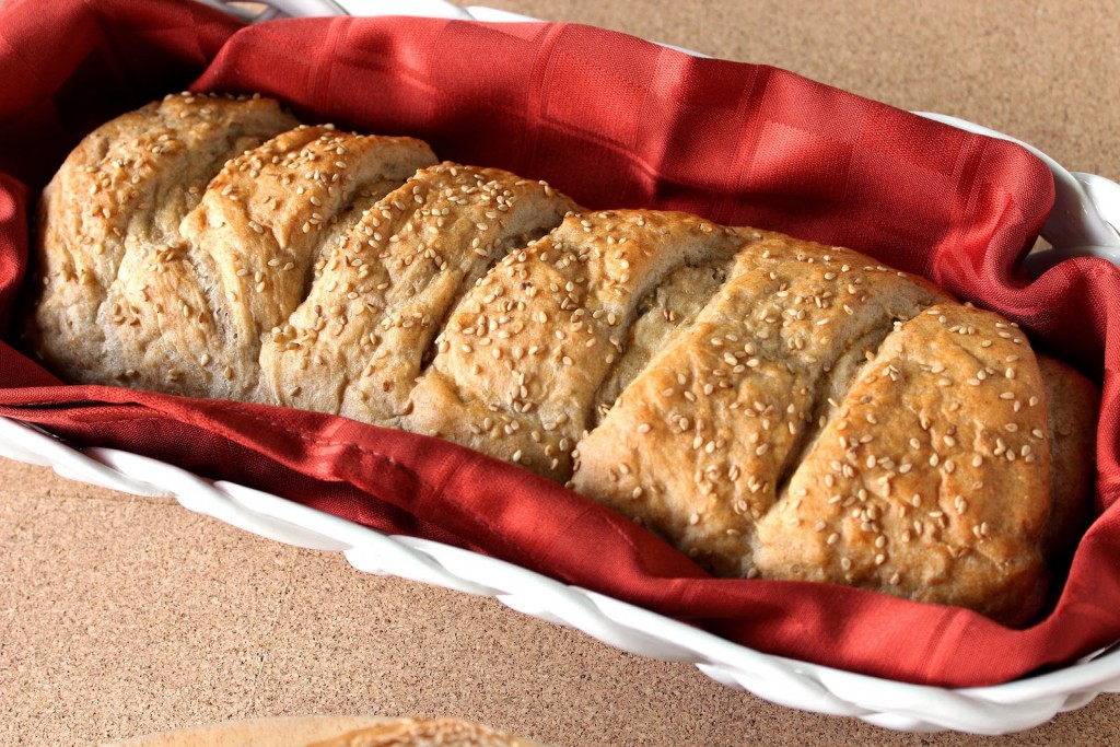 Loaf of whole wheat French bread in a bread basket with an orange napkin.