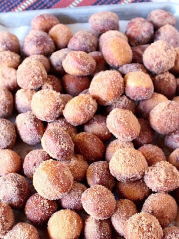 An overhead photo of a baking sheet filled with Apple Cider Donut Holes topped with cinnamon sugar.