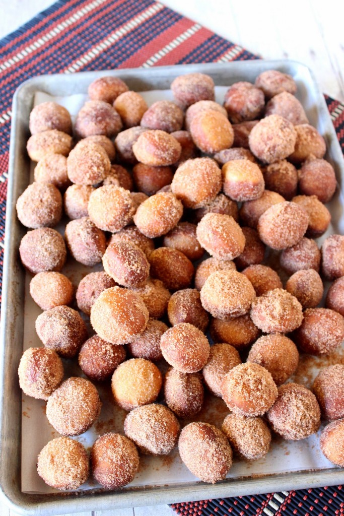 An overhead photo of a baking sheet filled with Apple Cider Donut Holes topped with cinnamon sugar.