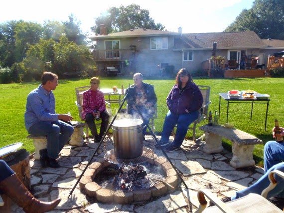 People sitting around a firepit as a low country boil is cooking in a giant pot.