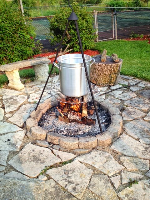 A large pot and a firepit tripod outside for cooking a low-country seafood boil.