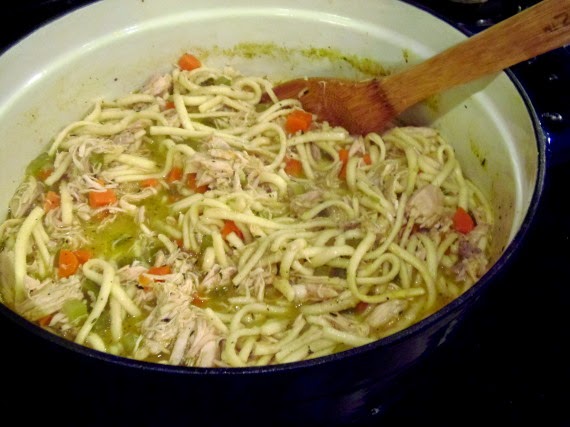 Finished Carrot Ginger Chicken Noodle Stew in a pot with a wooden spoon.