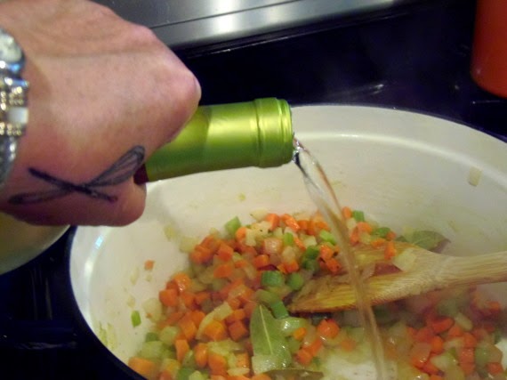 White wine being poured into a soup pot.