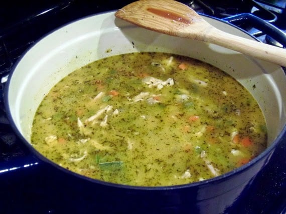 A wooden spoon resting on the side of a soup pot.