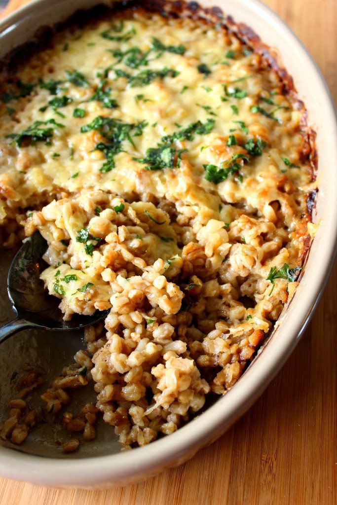 An overhead photo of a cheesy Farro and Onion Casserole with a serving spoon.