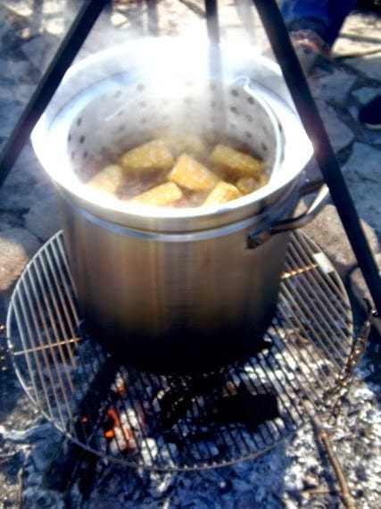 A huge steamy pot of low-country seafood boil being cooked over and outdoor firepit.