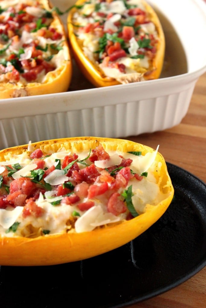 A vertical photo of spaghetti squash Alfredo. Two are in a casserole dish and one is on a plate.