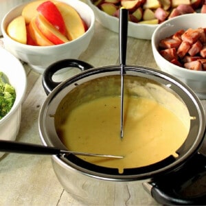 A silver fondue pot filled with Swiss Cheese Fondue and two fondue forks.