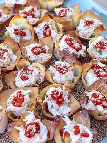 A platter of Baked Crab Rangoon on a bed of sesame seeds.