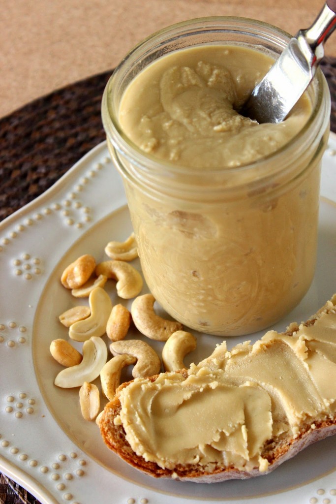 Looking into a jar of  Honey Cashew Peanut Butter with a knife and a slice of bread.