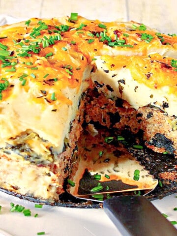 A round Layered Turkey Meatloaf on a square white platter with a serving spatula.