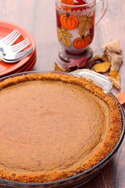 A Pumpkin Praline Pie with dried autumn leaves in the background.