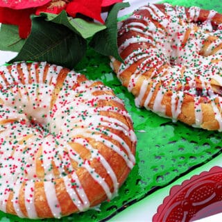 A horizontal photo of a green glass plate with two Cranberry Kringle with a white chocolate drizzle and sprinkles.