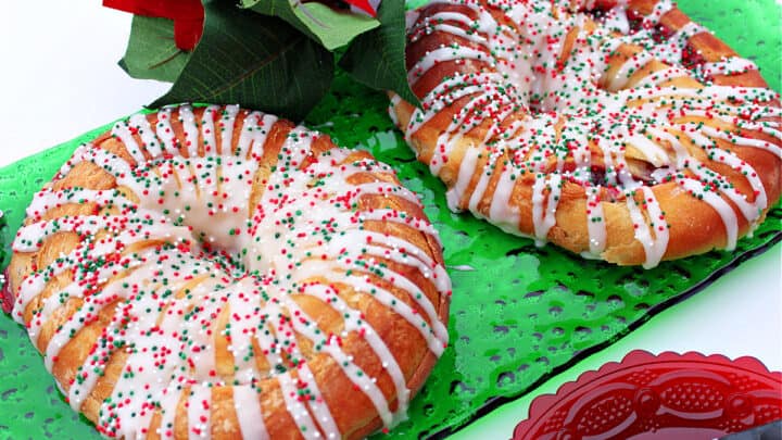 A horizontal photo of a green glass plate with two Cranberry Kringle with a white chocolate drizzle and sprinkles.