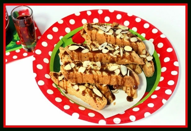 A stack of Amaretto Coconut Biscotti on a red and white polka dot plate and the cookies are drizzled with caramel.