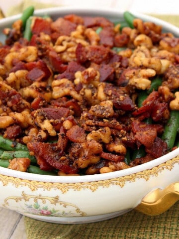 A fancy dish filled with Honey Green Beans topped with Bacon and Walnuts