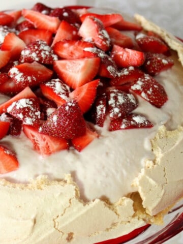 A closeup of a Pavlova with Yogurt and Strawberries topped with confectioners sugar.