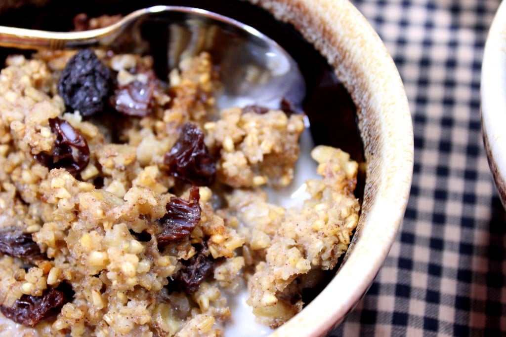 Closeup picture of baked steel cut oatmeal with raisins in a brown bowl.