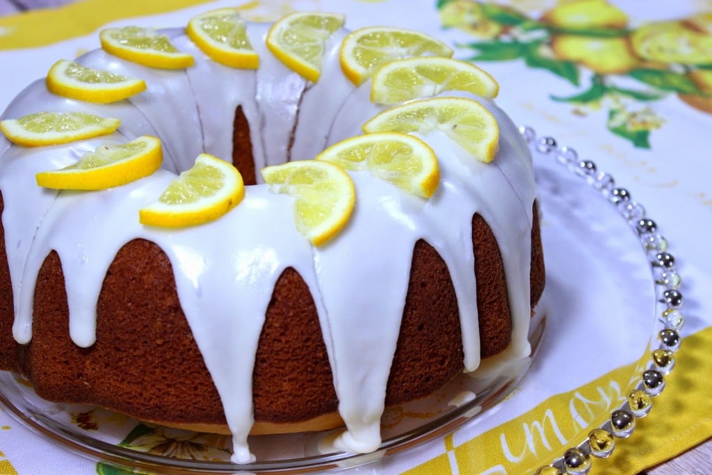 A glazed Meyer Lemon Poundcake on a glass plate with a lemon napkin underneath.