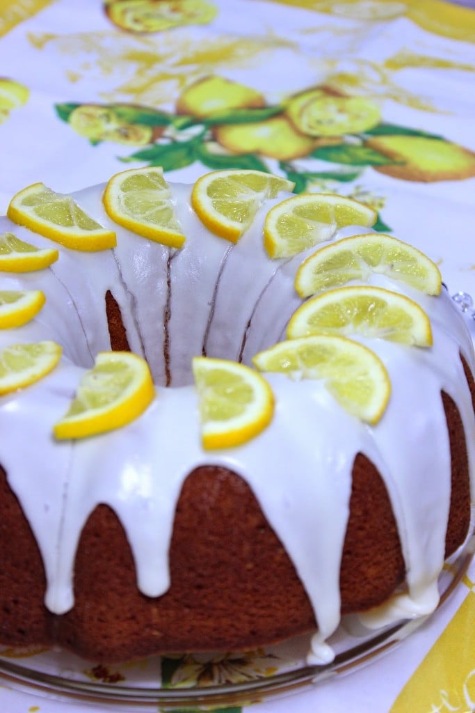 A Meyer Lemon Poundcake on a glass plate with lemon slices on top.