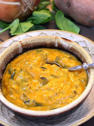 A brown blow filled with Sweet Potato and Wild Rice Chowder along with a spoon.